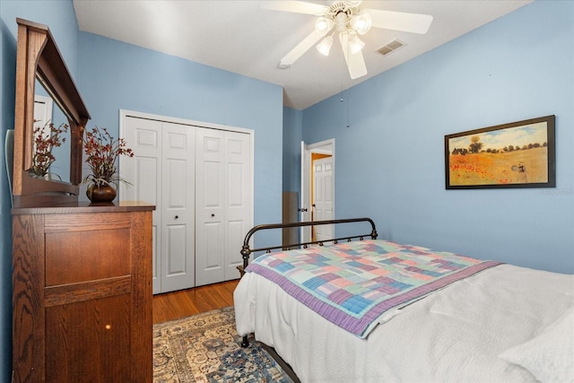 bedroom with a closet, wood finished floors, visible vents, and a ceiling fan