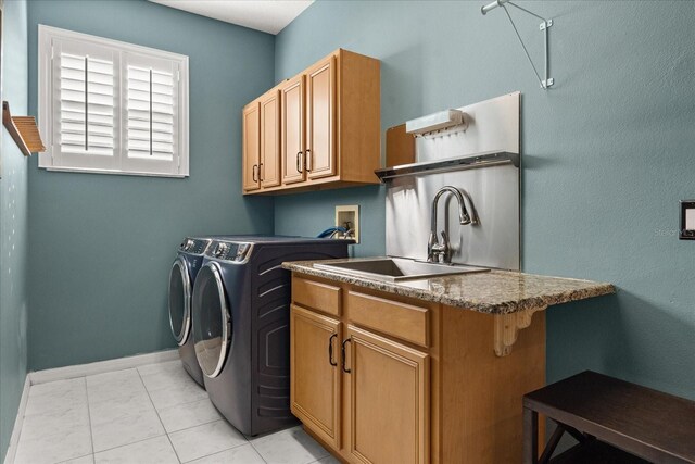 clothes washing area featuring baseboards, cabinet space, a sink, and washing machine and clothes dryer