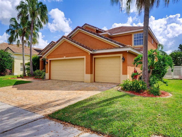 view of front of property with a garage, fence, decorative driveway, a front lawn, and stucco siding