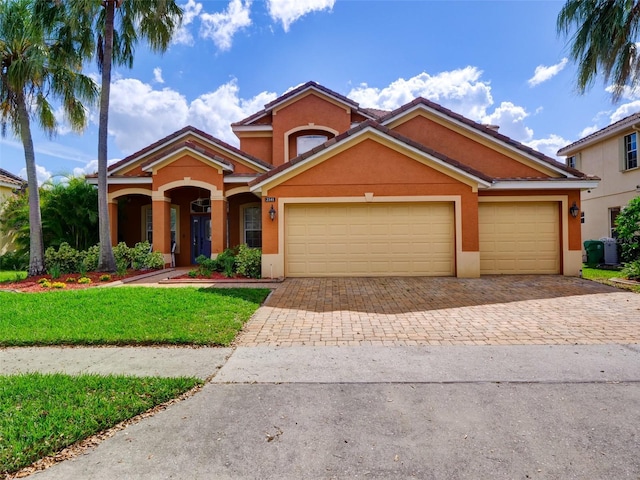 view of front of property with decorative driveway, central air condition unit, stucco siding, a front yard, and a garage