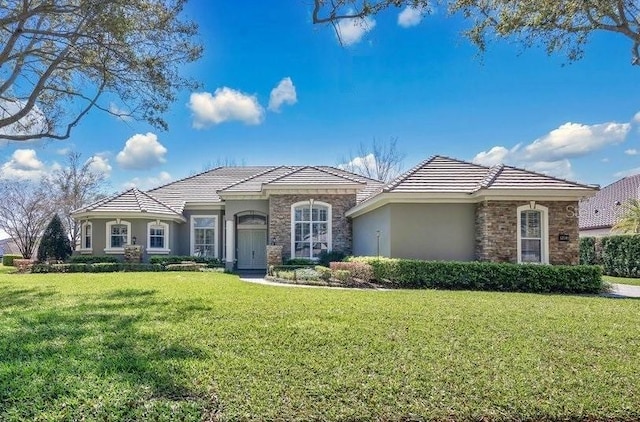 view of front of house featuring stucco siding, stone siding, a front lawn, and a tiled roof