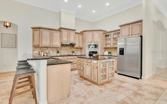 kitchen featuring arched walkways, a sink, glass insert cabinets, under cabinet range hood, and appliances with stainless steel finishes