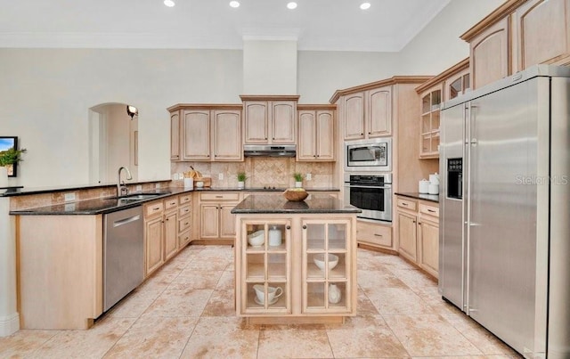 kitchen with arched walkways, a sink, under cabinet range hood, built in appliances, and backsplash