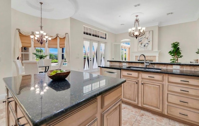 kitchen featuring visible vents, a center island, a chandelier, dark stone counters, and a sink