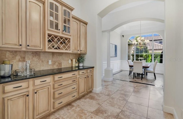 bar with light tile patterned flooring, arched walkways, wainscoting, a decorative wall, and tasteful backsplash