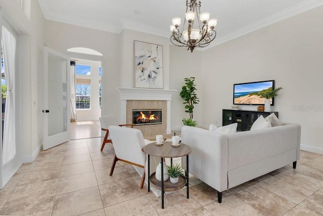 living area with baseboards, an inviting chandelier, light tile patterned flooring, ornamental molding, and a tile fireplace