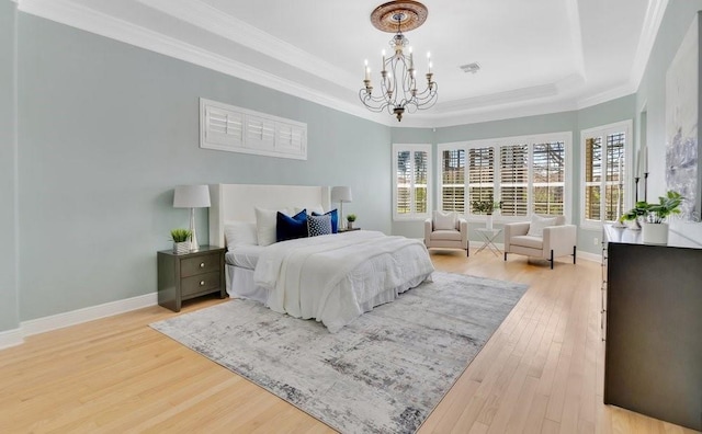 bedroom with multiple windows, a raised ceiling, and light wood finished floors