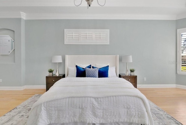 bedroom featuring ornamental molding, baseboards, and wood finished floors