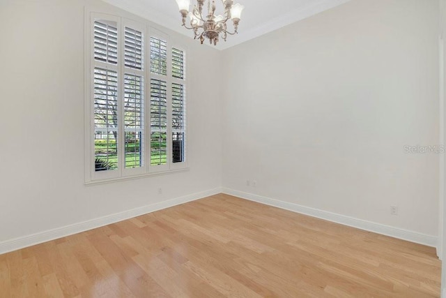 empty room with baseboards, a chandelier, crown molding, and light wood finished floors