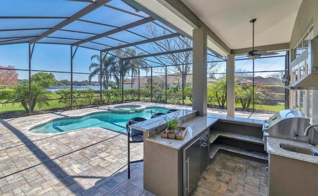 view of swimming pool with a pool with connected hot tub, an outdoor kitchen, a grill, a lanai, and a patio area