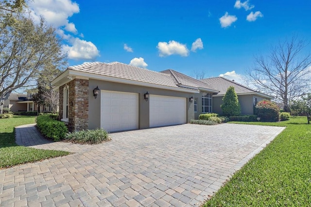 ranch-style house featuring a tile roof, stucco siding, decorative driveway, stone siding, and an attached garage