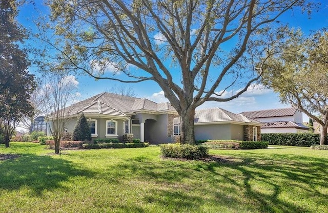 view of front of home with stucco siding, a tile roof, and a front lawn