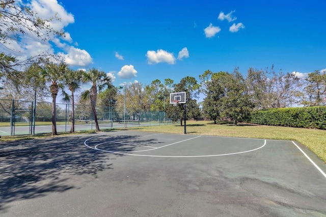 view of sport court with community basketball court, fence, and a lawn