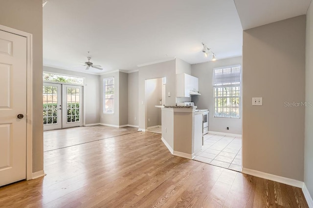 kitchen featuring plenty of natural light, white cabinets, light wood-type flooring, white range, and under cabinet range hood