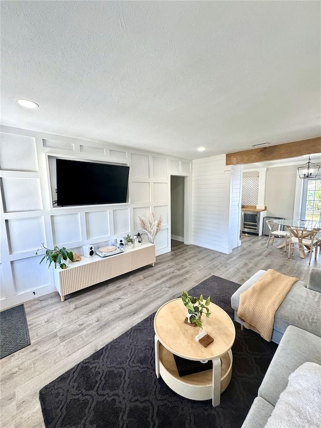 living room with a textured ceiling, built in shelves, wood finished floors, and a decorative wall