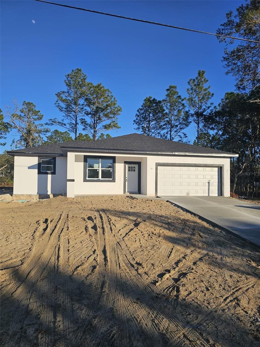 single story home featuring a garage, driveway, and stucco siding