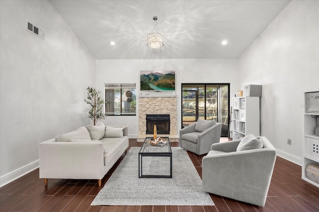 living area featuring a stone fireplace, recessed lighting, dark wood-type flooring, visible vents, and baseboards