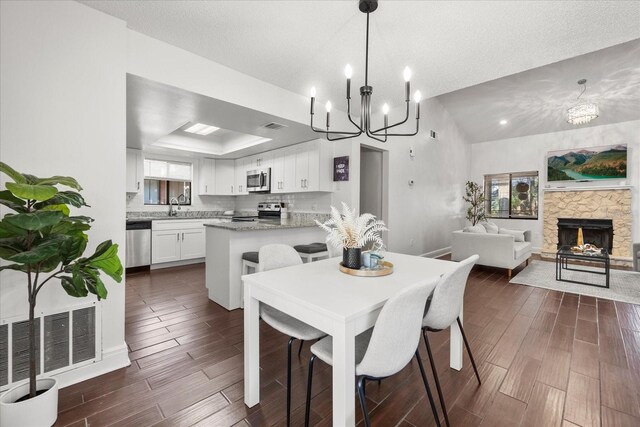 dining space featuring a tray ceiling, an inviting chandelier, visible vents, and wood tiled floor