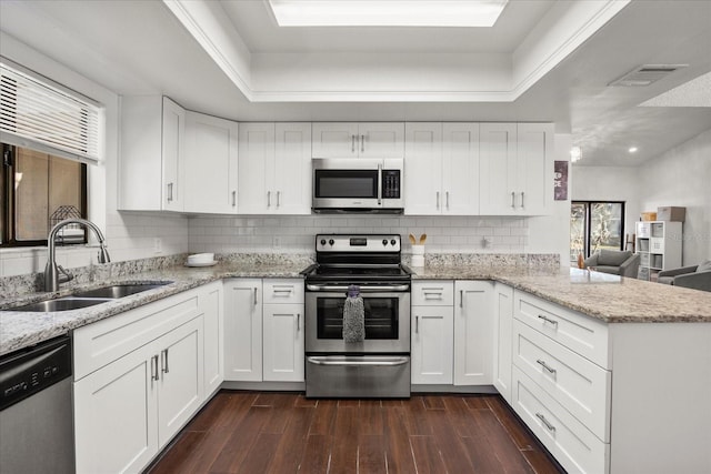 kitchen with stainless steel appliances, decorative backsplash, dark wood-type flooring, a sink, and a peninsula