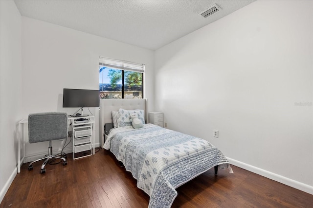 bedroom with baseboards, visible vents, a textured ceiling, and hardwood / wood-style floors