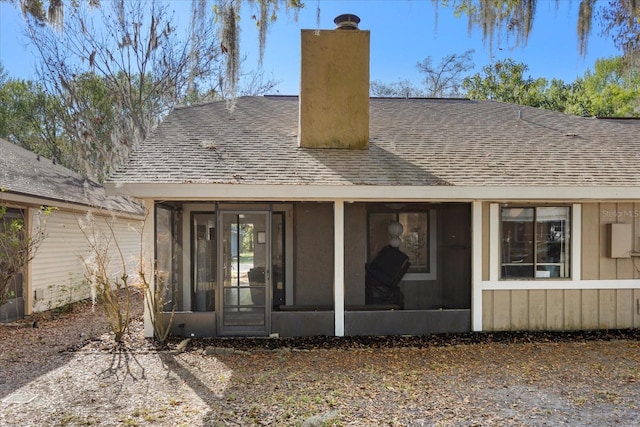 exterior space featuring a sunroom, roof with shingles, and a chimney