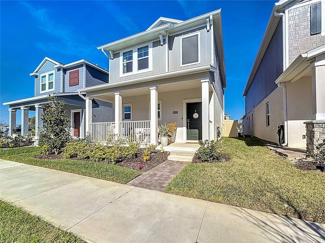 view of front of property with covered porch, a front yard, and stucco siding