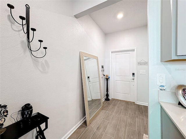 doorway featuring baseboards and wood finish floors