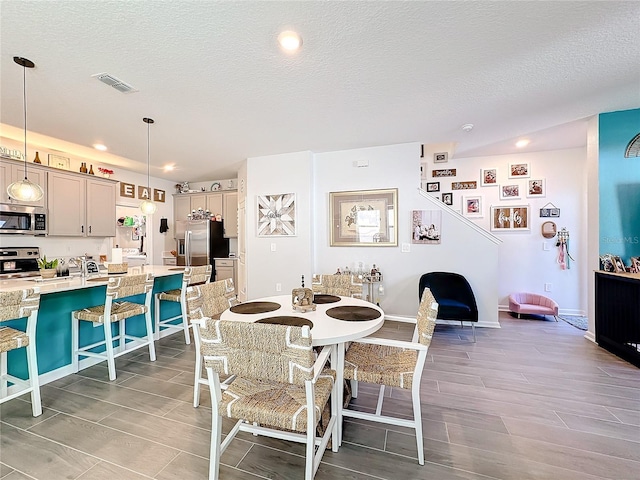 dining room featuring baseboards, visible vents, wood tiled floor, a textured ceiling, and recessed lighting