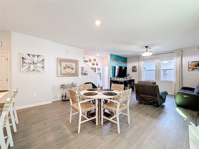 dining area featuring a textured ceiling, wood finish floors, and baseboards