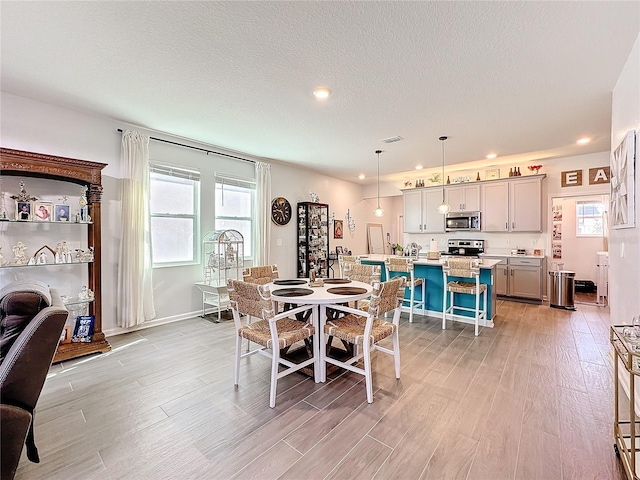 dining area featuring light wood-style floors, a wealth of natural light, and a textured ceiling