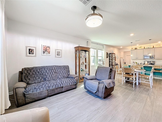 living room with wood tiled floor, visible vents, and a textured ceiling