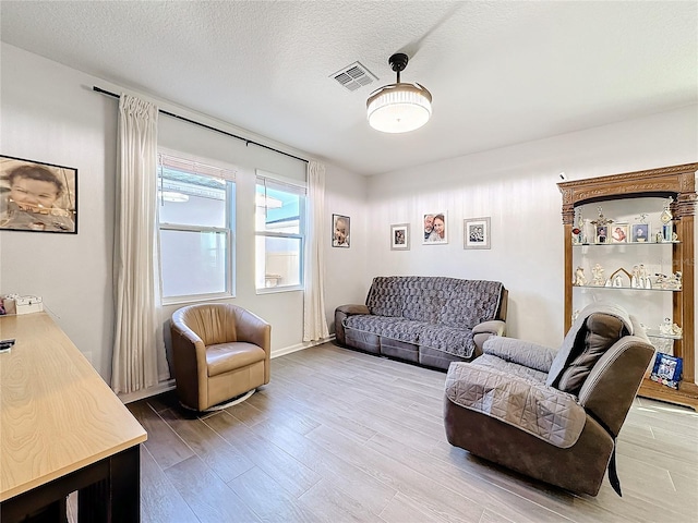 living area featuring a textured ceiling, visible vents, and wood finished floors