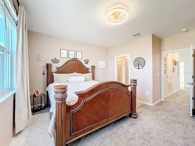 bedroom with a textured ceiling, baseboards, visible vents, and light colored carpet