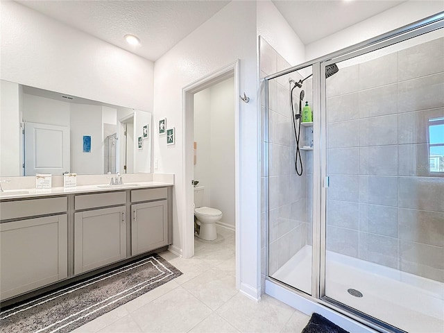 bathroom with toilet, a stall shower, vanity, tile patterned flooring, and baseboards