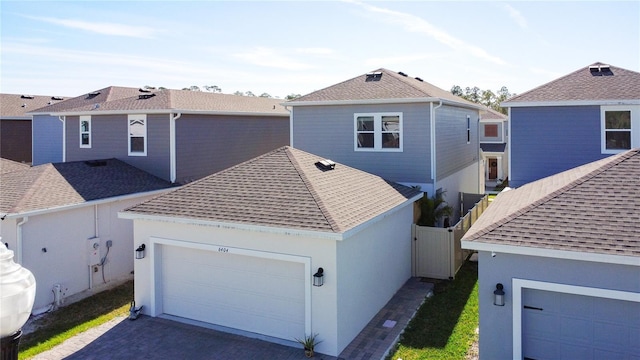 view of front facade with a shingled roof, driveway, an attached garage, and fence