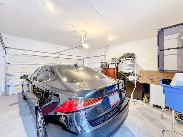 garage featuring concrete block wall and a garage door opener