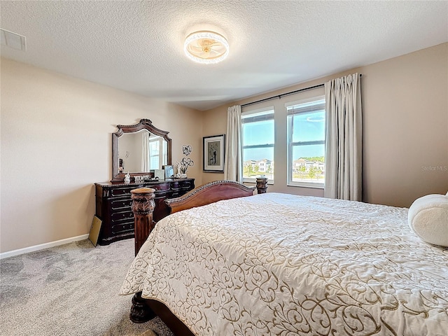 bedroom featuring a textured ceiling, carpet, visible vents, and baseboards