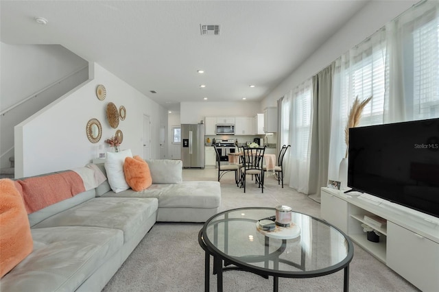 living room featuring recessed lighting, visible vents, light carpet, and stairs