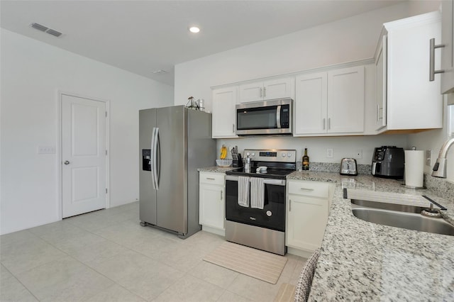 kitchen featuring light stone counters, visible vents, appliances with stainless steel finishes, white cabinets, and a sink