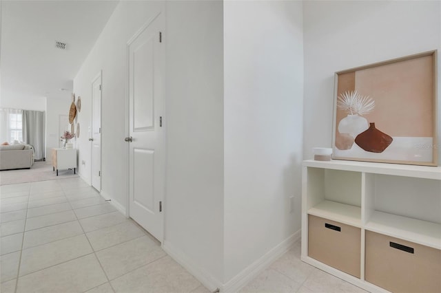 hall with light tile patterned floors, visible vents, and baseboards