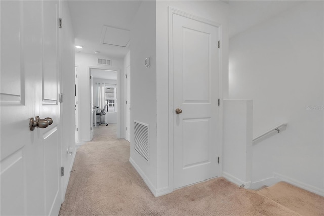 corridor with attic access, light colored carpet, and visible vents