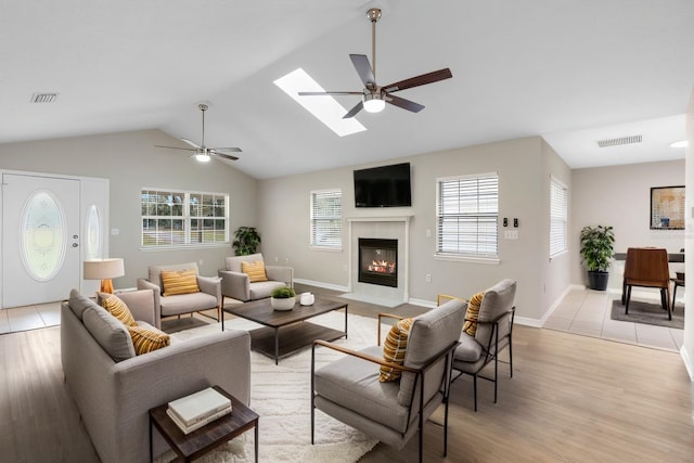 living area with a ceiling fan, a wealth of natural light, and visible vents