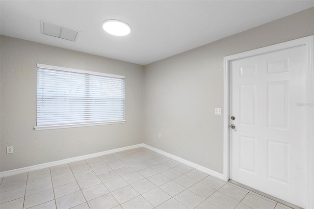 empty room with light tile patterned flooring, visible vents, and baseboards