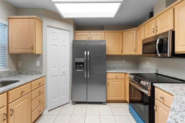 kitchen with light brown cabinetry, appliances with stainless steel finishes, light tile patterned flooring, a sink, and light stone countertops