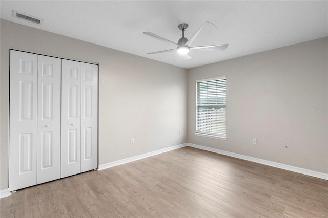 unfurnished bedroom with a closet, visible vents, ceiling fan, light wood-type flooring, and baseboards