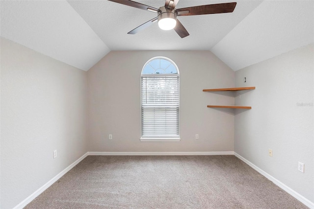 carpeted empty room with a textured ceiling, baseboards, vaulted ceiling, and a ceiling fan