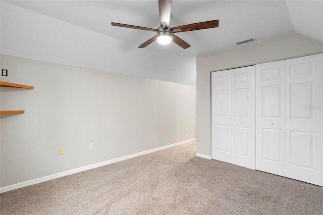 unfurnished bedroom with lofted ceiling, carpet flooring, visible vents, baseboards, and a closet