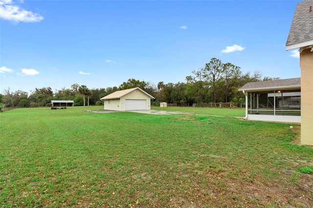 view of yard with a garage, an outbuilding, and a sunroom