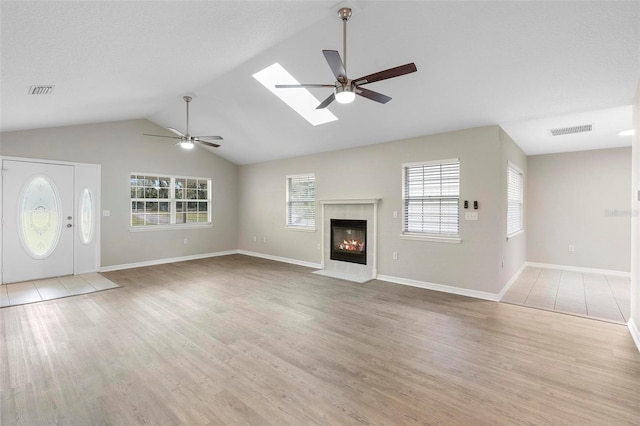 unfurnished living room featuring a ceiling fan, visible vents, a fireplace, and wood finished floors