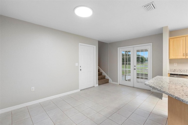 unfurnished dining area with light tile patterned flooring, visible vents, baseboards, french doors, and stairway